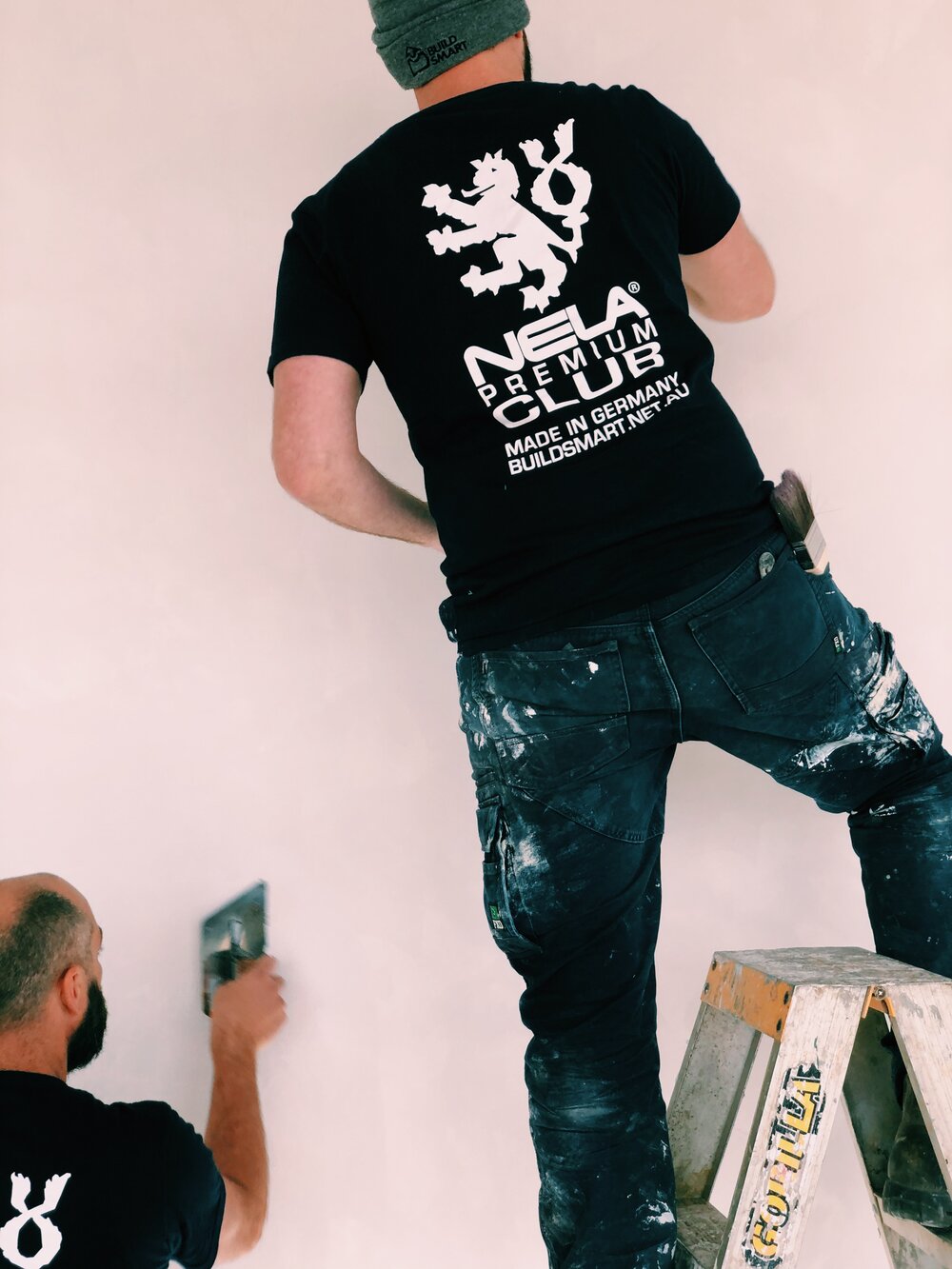 NELA Premium T-Shirt black with white NELA logo, worn by plasterers on site